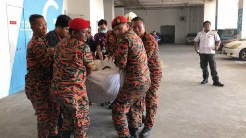 中国侨网消防员费力的抬起男子。(马来西亚《中国报》)
