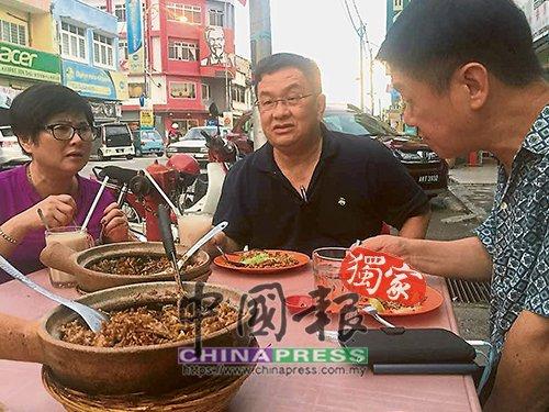中国侨网李志亮（右起）与游上运，在金宝叙旧时共同享用瓦煲鸡饭。（马来西亚《中国报》）
