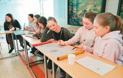 中国侨网芬兰当地小学邀请于韦斯屈莱市中国学生学者联合会去他们那里参加国际日活动。图为该校五六年级学生在摹写志愿者谢宝玲交给他们的中国书法。