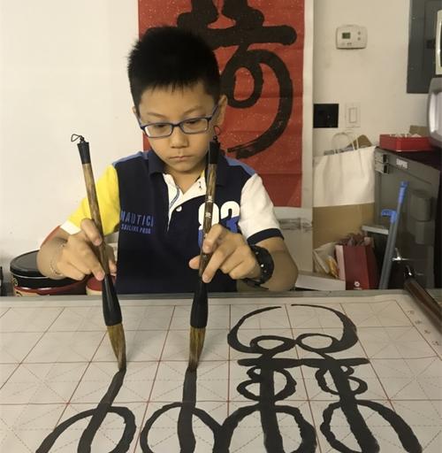 中国侨网于昊辰小小年纪喜爱双手书法，以此了解和学习中国文化。（美国《世界日报》/刘大琪 摄）