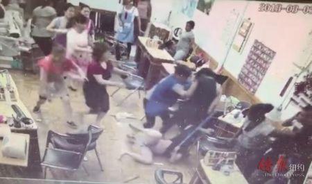 中国侨网华裔指甲店女员工被叫来的帮凶（黑衣者）打倒在地并拖拉。（图片来源：纽约《侨报》）
