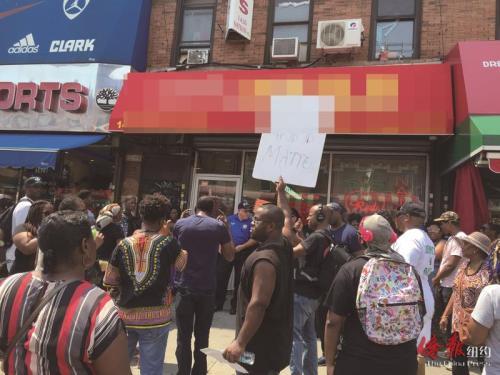 中国侨网示威者在店前举着标语高呼口号，抗议指甲店员工打人。(纽约《侨报》/崔国萁 摄)
