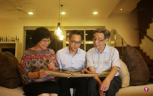 中国侨网何国元医生（中）和父母一起翻阅旧相簿，温馨往事纷纷涌上心头。（图片来源：新加坡《联合早报》）