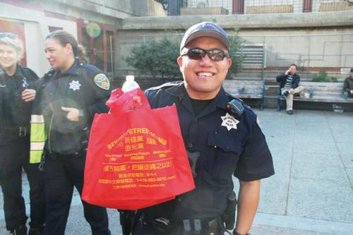 中国侨网华埠警员马健明参与小区外展，拿着防范金光党骗案的宣传袋子。(美国《世界日报》/李晗 摄)