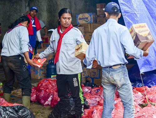 中国侨网12月25日，在印度尼西亚万丹省板底兰县的灾民安置点，参与赈灾的工作人员为灾民搬运食物。新华社记者杜宇摄