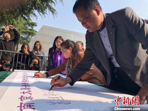 中国侨网 5日是清明节。清晨，南京大屠杀幸存者后代在“南京大屠杀幸存者后代传承记忆行动”卷轴上悉数落笔签名，以表达参与到南京大屠杀历史记忆传承行动中来。 朱晓颖 摄