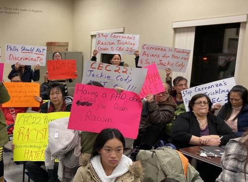 中国侨网纽约华裔家长在第22学区教育理事会开会现场高举抗议牌。(美国《世界日报》/黄伊奕 摄)