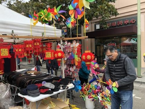 中国侨网年货摊主Sam(右)说,摊位在11日晚发生奇怪的偷窃案,游民偷走购物袋,估计是为遮风挡雨取暖。(美国《世界日报》刘先进/摄)