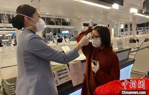 中国侨网春秋航空日本工作人员为旅客测量体温。　春秋航空供图　摄