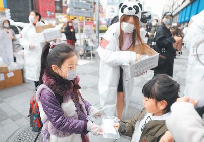 中国侨网在日华侨华人发起的志愿者团体“口罩熊猫行动小组”在日本东京池袋站前向当地民众免费发放口罩。图为一名小志愿者（左）向当地小朋友发放儿童用口罩。 新华社记者 杜潇逸摄