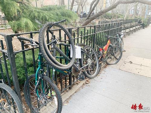 中国侨网纽约华埠哥伦布公园的栅栏上锁着不少违规停放的单车。（美国《侨报》/杨澄雨 摄）