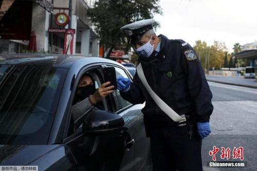 中国侨网当地时间11月7日，希腊雅典，一名警察正在检查司机证件，确定其出行目的。为遏制新冠疫情，自当地时间7日早晨6时起，希腊全国进入为期三周的封锁状态。新的限制措施将禁止区域间的旅行。