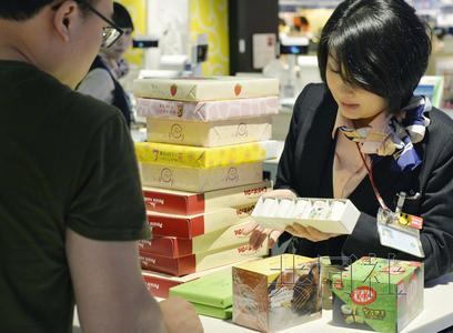 成田机场免税店内一名店员正在应对外国游客购物。(共同社)