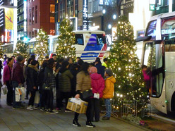 图为1月在东京银座，购物的中国游客们与停在路边的旅游大巴。