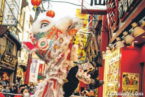 日本横滨市的唐人街洋溢着浓郁的春节气氛，舞狮队在餐馆外采青贺岁。（路透社）
