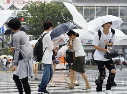 图为在台风“蒲公英”强风中紧持雨伞步行的人们。8月22日下午摄于东京涩谷。（日本共同社）