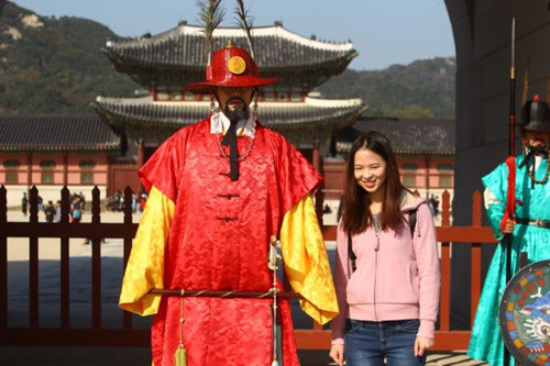 资料图片:在韩国首尔景福宫外,中国游客与韩国守城门将合影。(新华社/姚琪琳