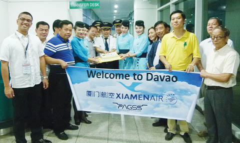 图为厦门航空公司首个厦门至纳卯市直飞航班的飞行员(中)昨晚在飞机抵达纳卯国际机场后,在机场内切蛋糕,庆祝首航成功。(菲律宾《商报》)