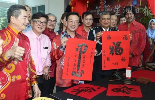 中国侨网卡立和黄惠康在吉隆坡警察总部展示黄惠康的挥毫作品。（马来西亚《星洲日报》）