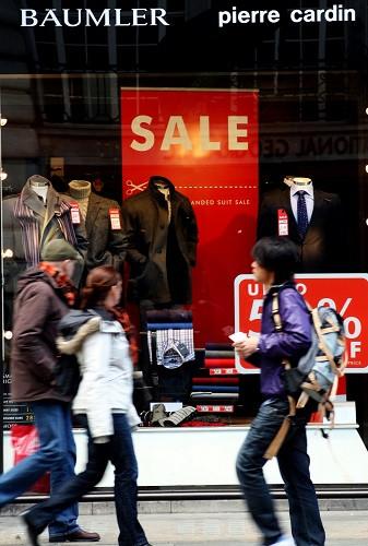 中国侨网资料图片：几名行人从英国伦敦著名的购物街——牛津街的一家服装店橱窗前经过。