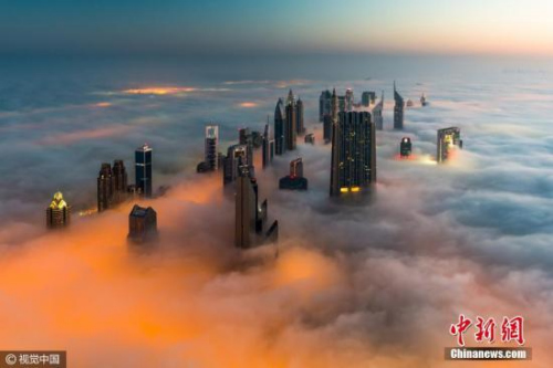 中国侨网资料图：大雾笼罩的迪拜摩天大楼宛如从狂暴的海洋中升起。摄影师在迪拜的摩天大楼上拍下了这组幻景。