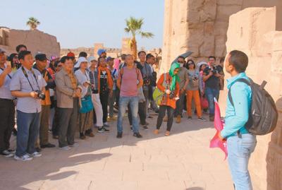 中国侨网在著名的埃及卡尔纳克神庙，来自中国的旅行团正在听导游对埃及历史的讲解。 　　本报记者 王云松摄 