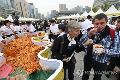 中国侨网资料图片：2016年10月26日，在首尔光化门广场，参加“第四届韩餐日”活动的外国游客品尝拌饭。（韩联社）