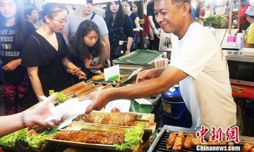 中国侨网资料图，泰国美食吸引大批食客。在泰国清迈夜市观光具有泰北特色的小吃品种繁多，炸猪皮、青辣椒酱、无骨炸鱼、芒果糯米饭、烤大头虾、烤鳄鱼串以及榴莲饼、蛋黄椰丝小饼等美味食品吸引众多游客。中新社记者 钱兴强 摄