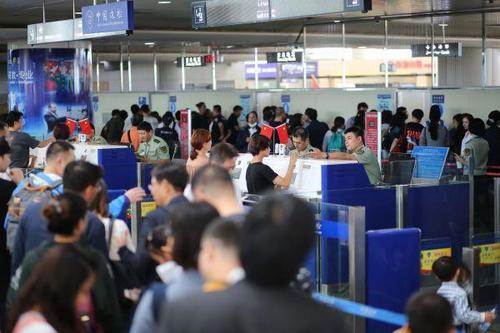 中国侨网9月30日,青岛机场边检站民警为出境游旅客办理通关手续。新华社发