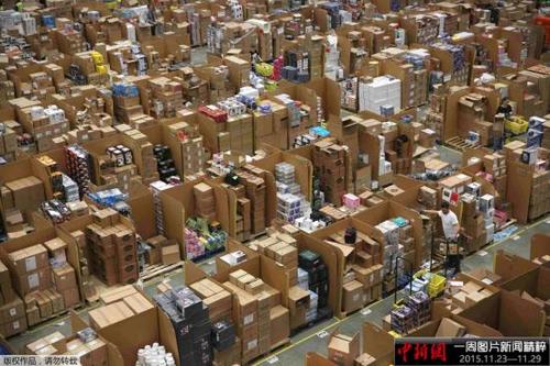 中国侨网当地时间11月27日，英国Hemel Hempstead的一处亚马逊仓库内，工作人员正忙着给商品装箱。当日，国外消费者迎来“黑色星期五”购物日。