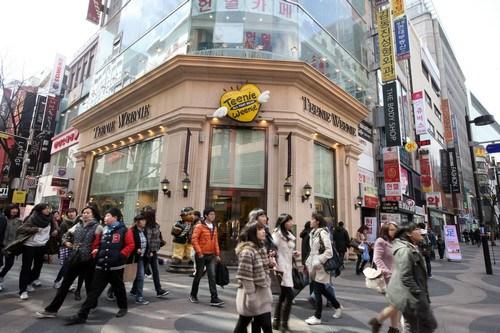 中国侨网资料图片：2011年3月2日，人群经过韩国首尔明洞购物区的一家服装店门口。新华社记者 何璐璐 摄