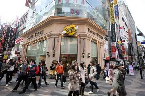 中国侨网资料图片:2011年3月2日,人群经过韩国首尔明洞购物区的一家服装店门口。新华社记者 何璐璐 摄