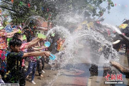 中国侨网资料图：泰国大象用鼻子向参加泼水节庆典的人群喷水。
