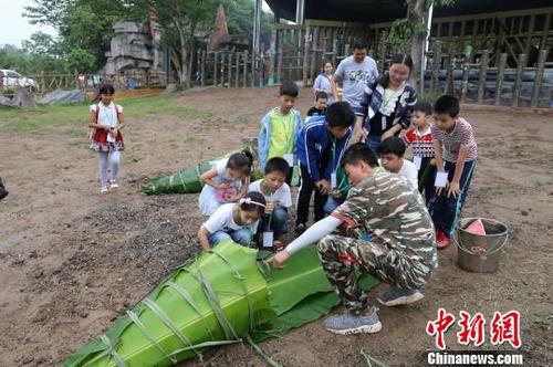 中国侨网图为饲养员与小朋友一起给非洲象包粽子。　韩璐　摄