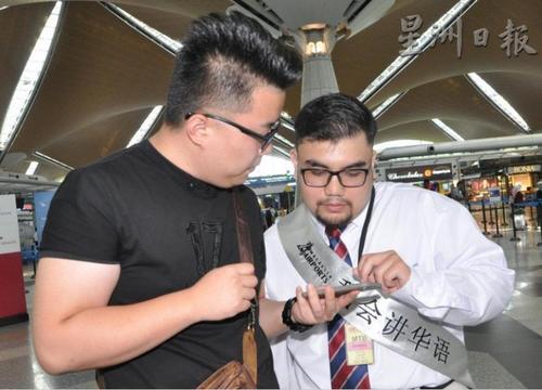 中国侨网“中文客服大使”邵菲在机场为游客提供帮助。（马来西亚《星洲日报》）