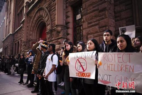 中国侨网当地时间3月14日，美国纽约杰奎琳肯尼迪高中的学生手举标语、高呼口号，要求政府采取更严格的控枪政策。 中新社记者 廖攀 摄