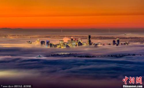 中国侨网资料图，一名来自英国的31岁摄影师Alexis Birkill拍摄了笼罩在浓雾下的温哥华绚丽美景，市中心的摩天大楼钻出云层宛若人间仙境。图片来源：CFP视觉中国