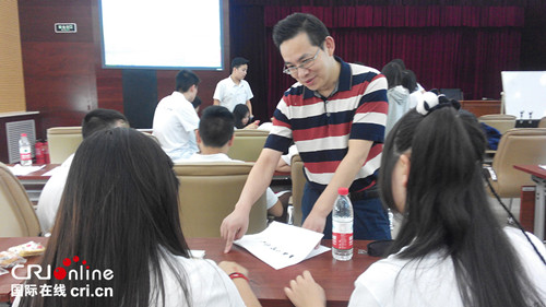 北京华文学院的汉语培训教师廖崇阳辅导营员学习汉语。(李红