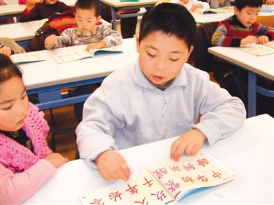 图为丹华学生正在认读《中华字经》上的汉字