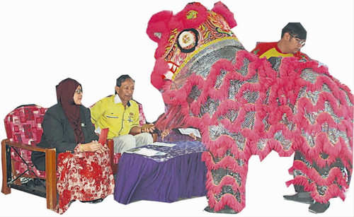 校长娜哈玛与家协主席沙立夫与醒狮互动并递上年柑。