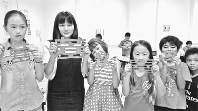 中国志愿者在老挝白云碧国际学校传播中国文化。图为志愿者胡佳佳（左二）和学生们展示他们的剪纸作品。中国青年志愿者赴老挝服务队供图