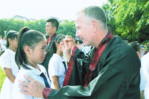 海南华侨中学三亚学校,一名身着传统汉服的外籍老师正在给学生点朱砂启智开蒙。(本报记者