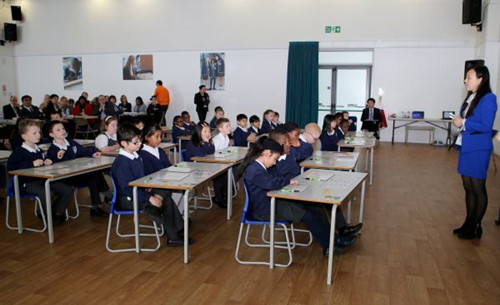 这是2015年3月17日，在英国伦敦东北部埃塞克斯郡的哈里斯小学，来自中国的数学老师林磊（右一）为三年级的小学生上数学课，教授“九九乘法表”在数学计算中的运用。