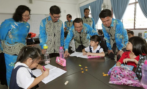 张盛闻（右起）、廖中莱与双溪龙华小的学生交流，了解他们在新华小上课的情形。（马来西亚《星洲日报》）