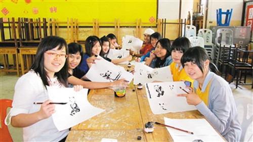 梁贞（左一）给泰国学生教画大熊猫。