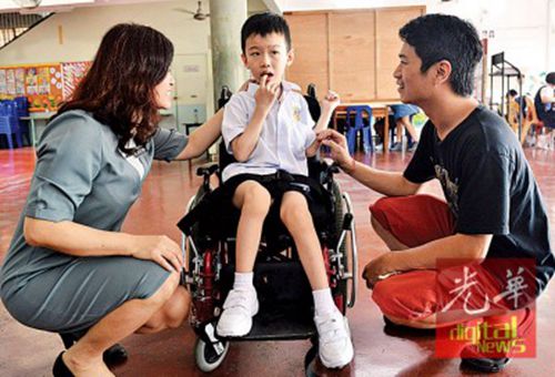 中国侨网伍绍伦把行动不便的奕丰送到益华就读,旁为李淑君。(马来西亚《光华日报》)