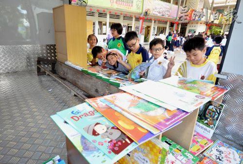 中国侨网学生对流动图书馆内的绘本爱不释手。（马来西亚《星洲日报》）