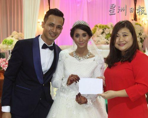 中国侨网阿里及丽玛夫妇在新婚典礼上，移交捐款给培风中学校长黄雪莱（右）。（马来西亚《星洲日报》）