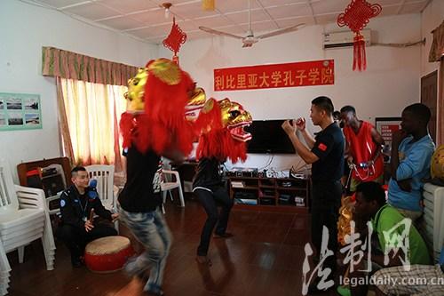 中国侨网图为防暴队员教授利比里亚大学孔子学院学生舞狮基本动作与技能。