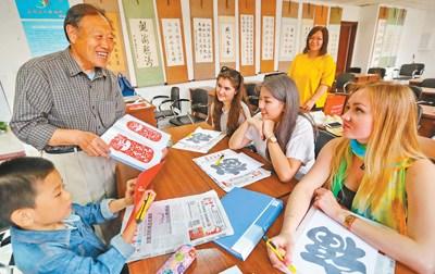 中国侨网图为秦皇岛市海港区燕大西苑社区居民教外国留学生学习剪纸。 本报记者 史自强摄